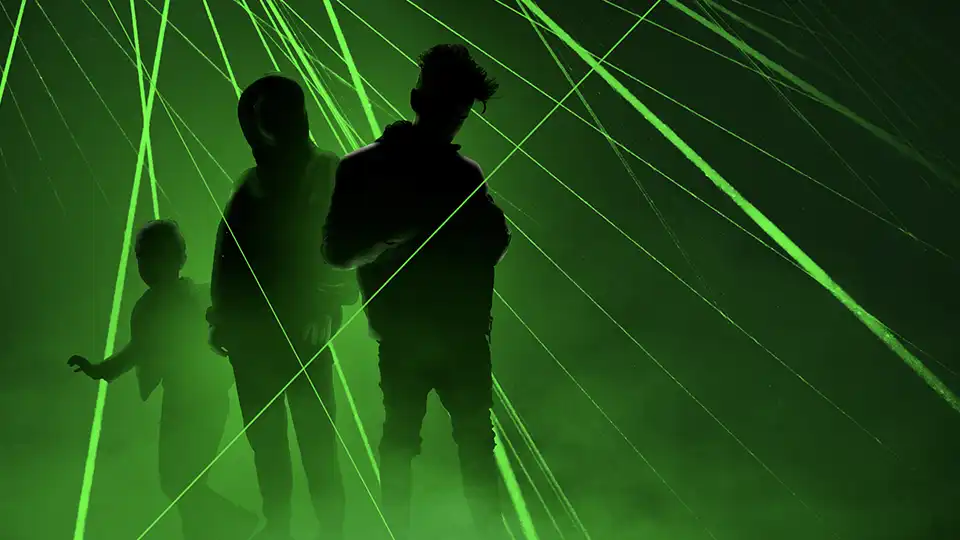 schwarze Silhouetten vor grünen Laserstrahlen